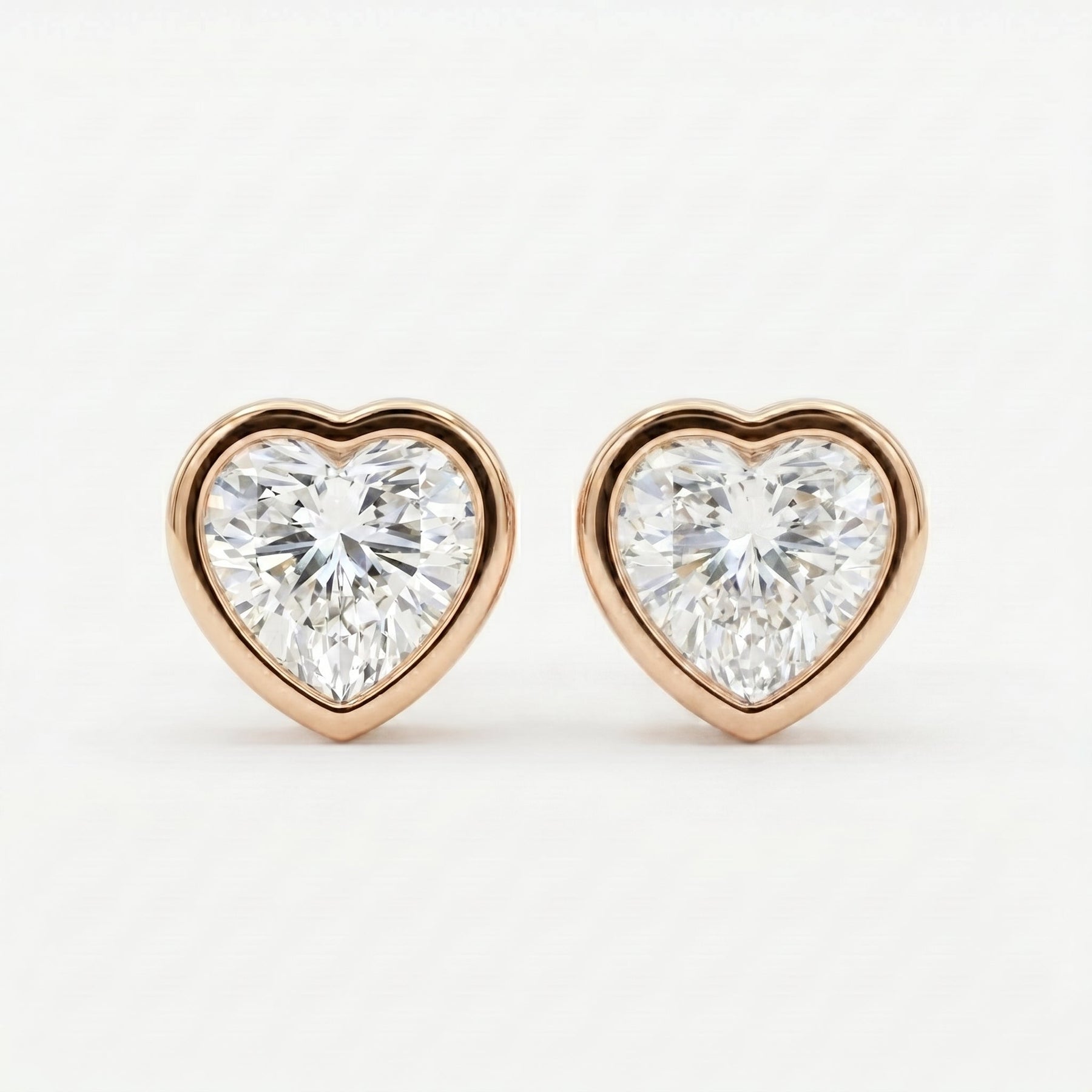 Heart-shaped diamond earrings with rose gold setting on a white background