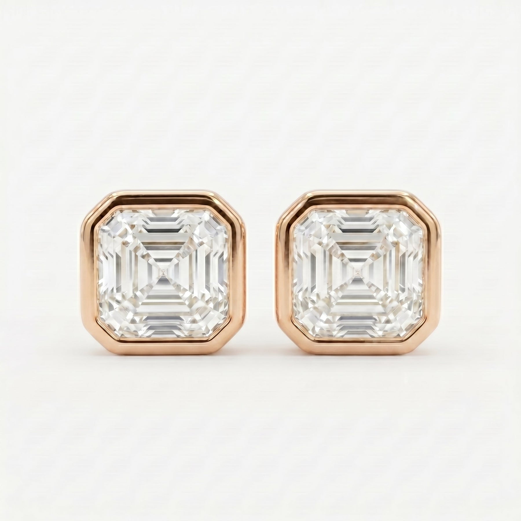 Pair of diamond stud earrings with rose gold setting on a white background