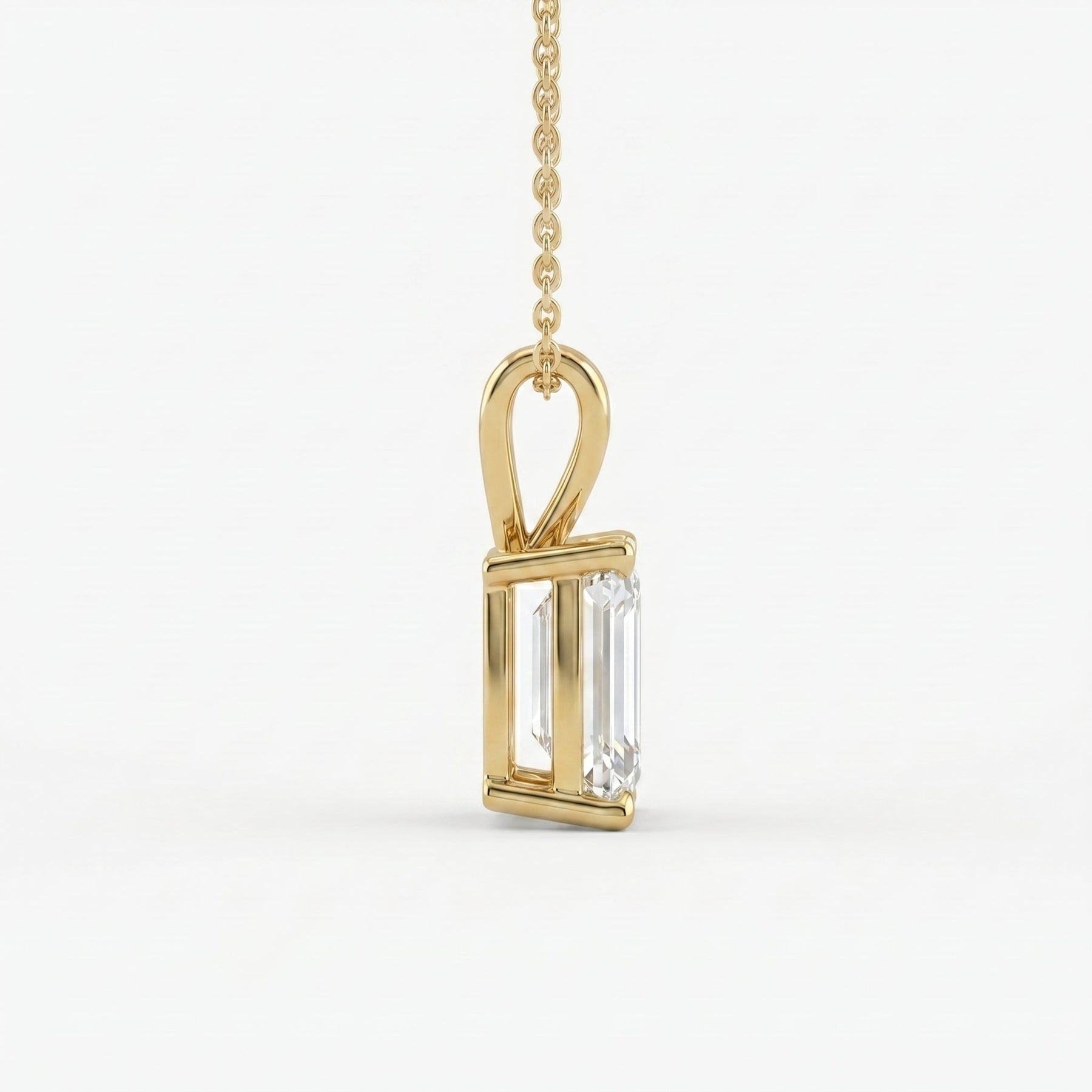 Gold pendant with a rectangular diamond on a white background