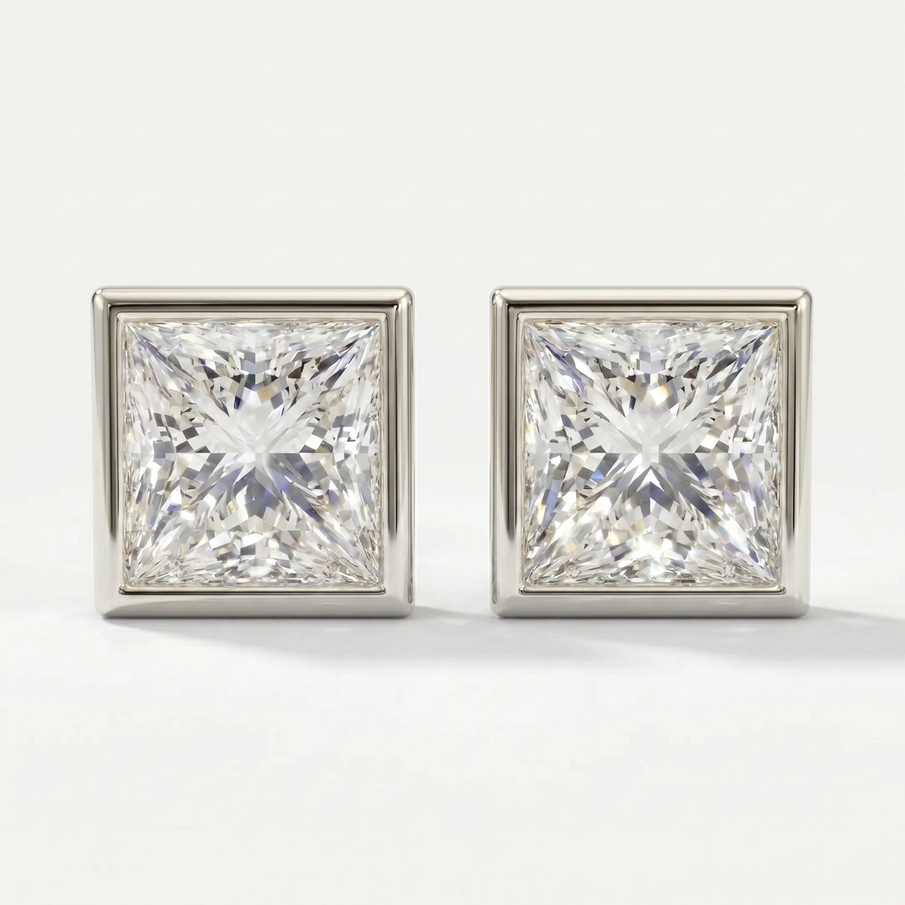 Pair of square-cut diamond earrings on a light gray background