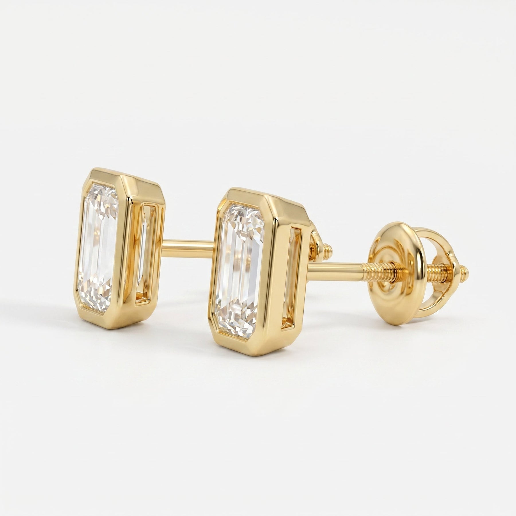 Gold earrings with emerald-cut diamonds on a white background