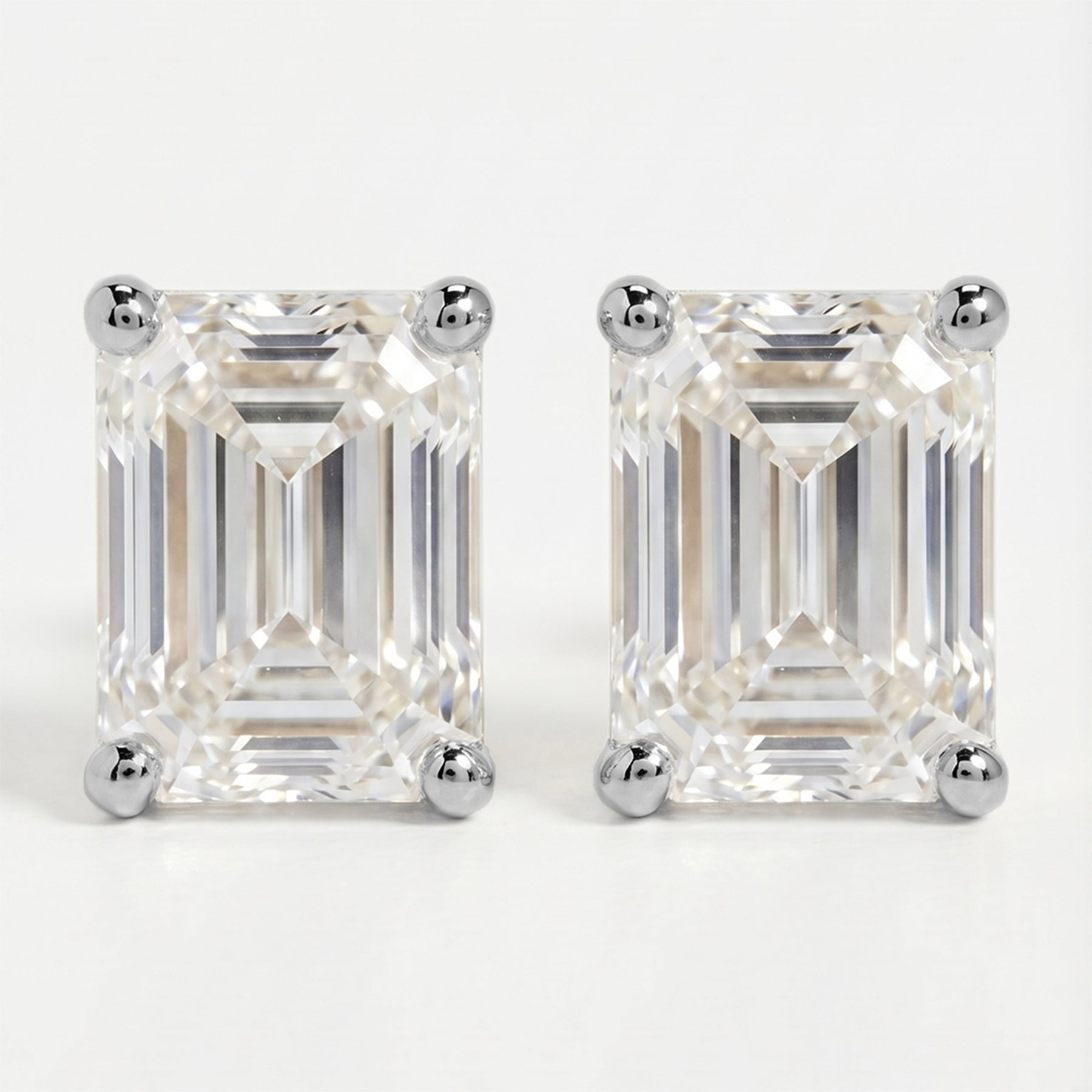 Pair of emerald-cut diamond earrings on a white background