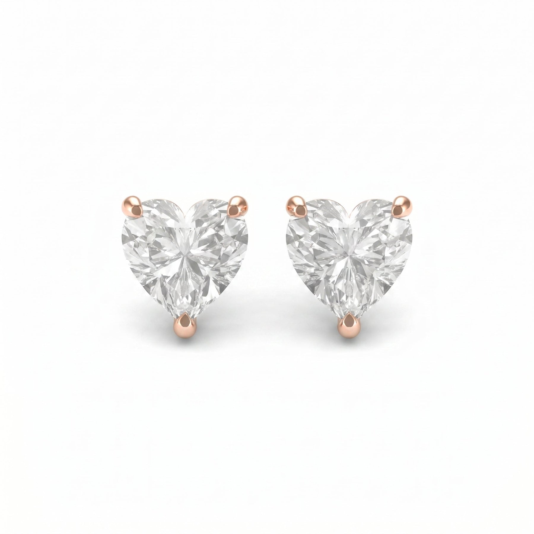 Heart-shaped diamond earrings with rose gold prongs on a white background
