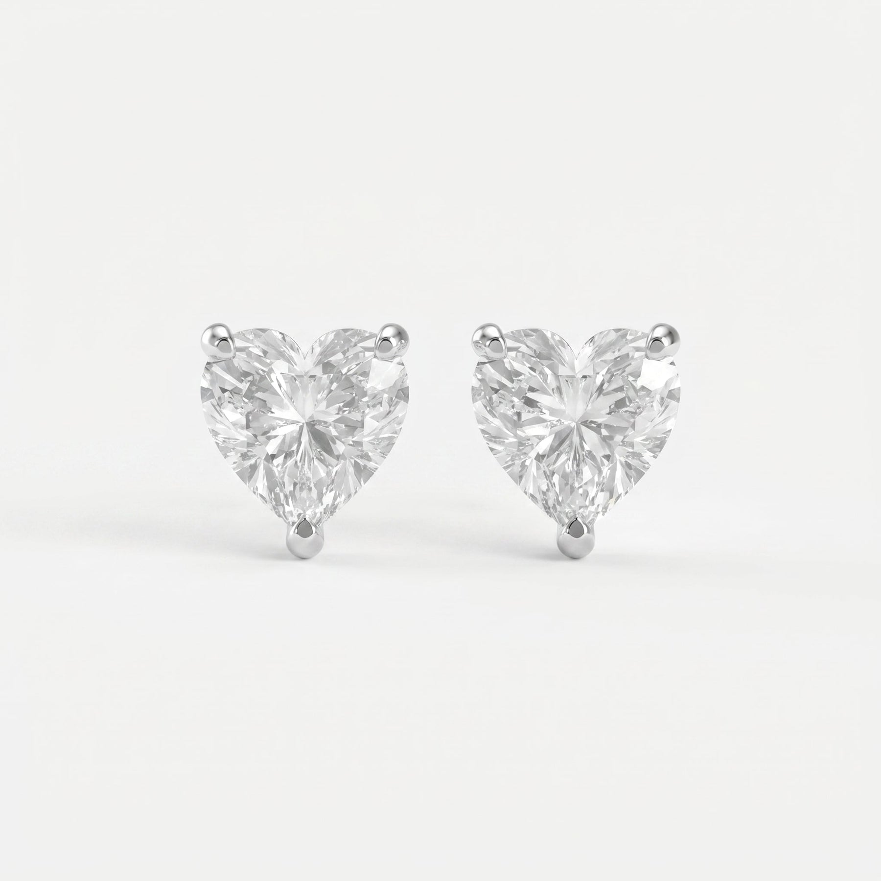 Heart-shaped diamond earrings on a light gray background