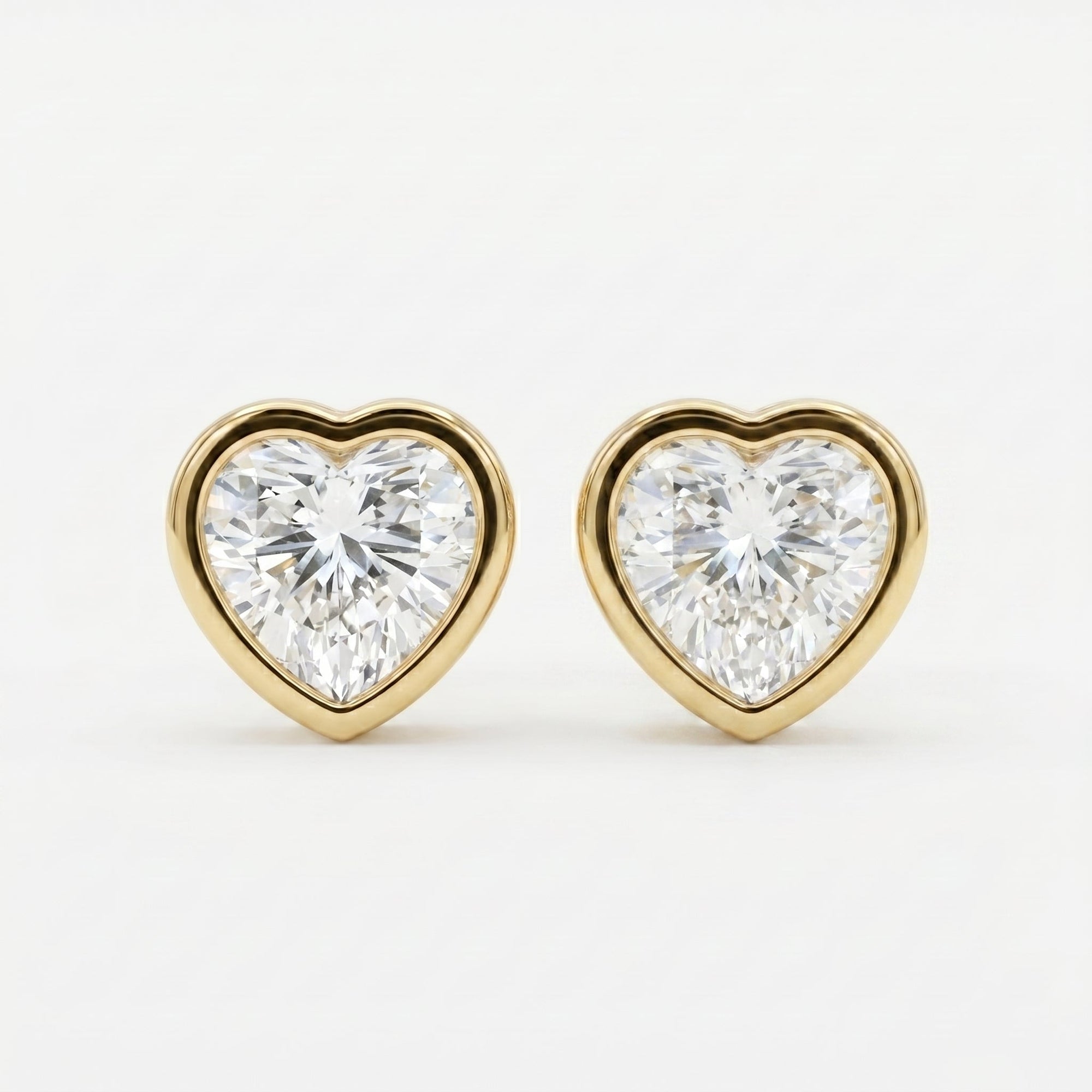 Heart-shaped diamond earrings with gold settings on a white background