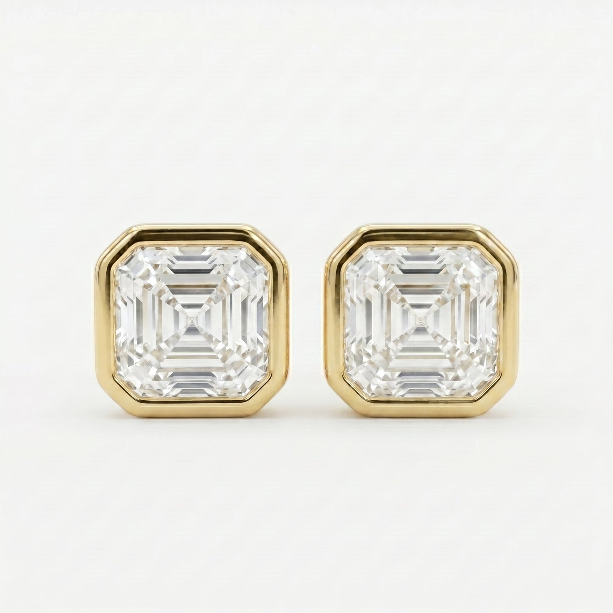 Gold earrings with Asscher-cut gemstones on a white background