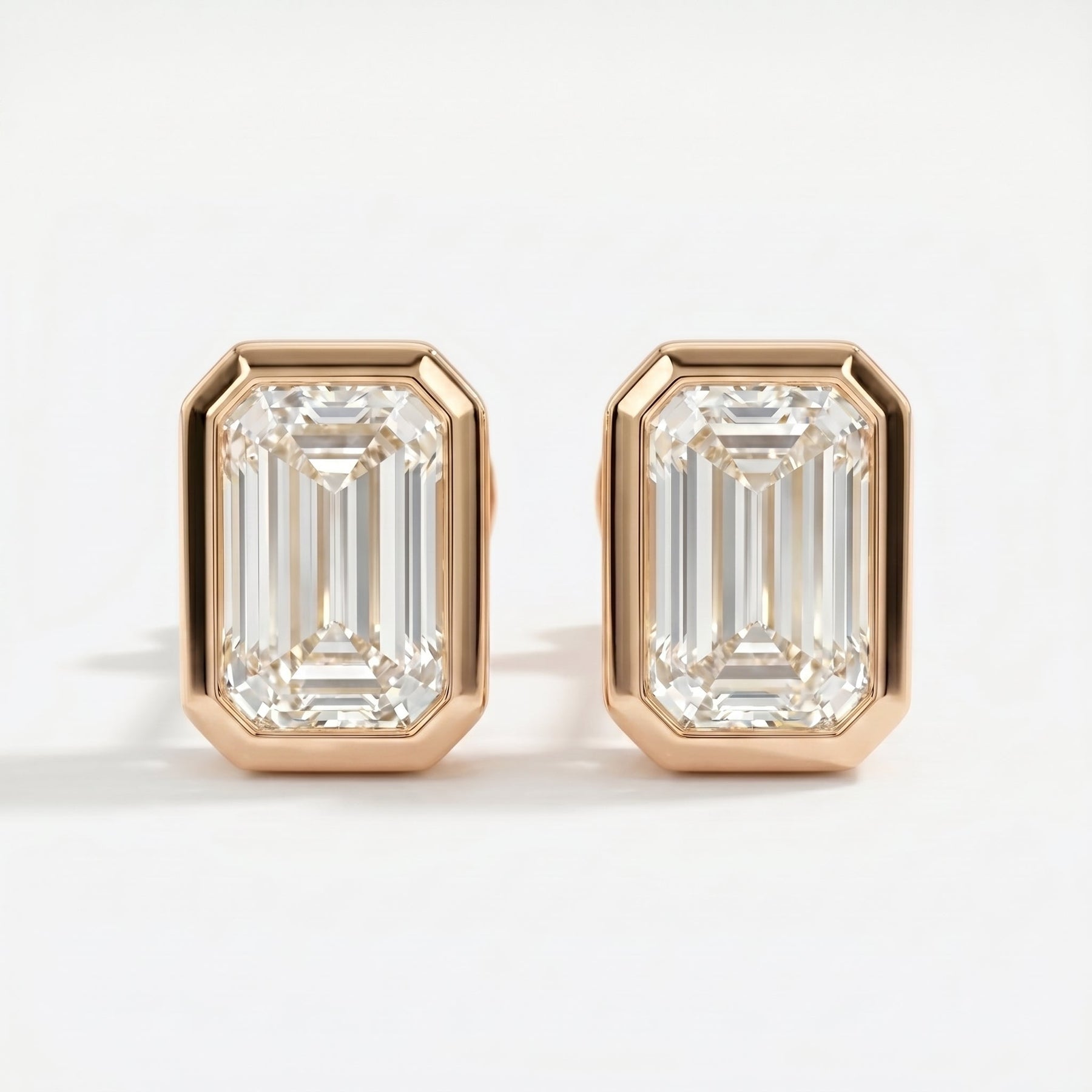 Pair of diamond earrings with rose gold setting on a white background