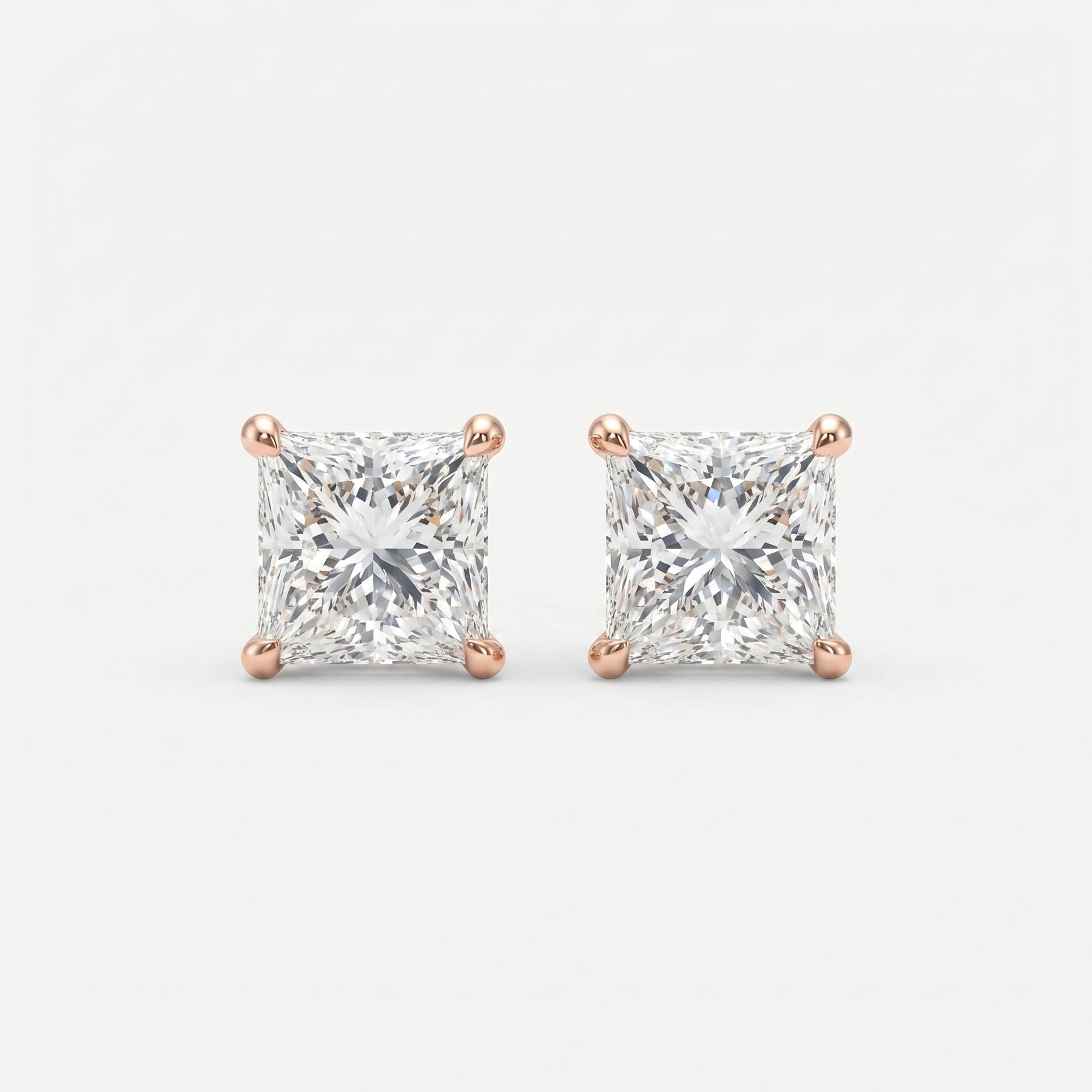 Pair of diamond stud earrings with rose gold prongs on a light gray background