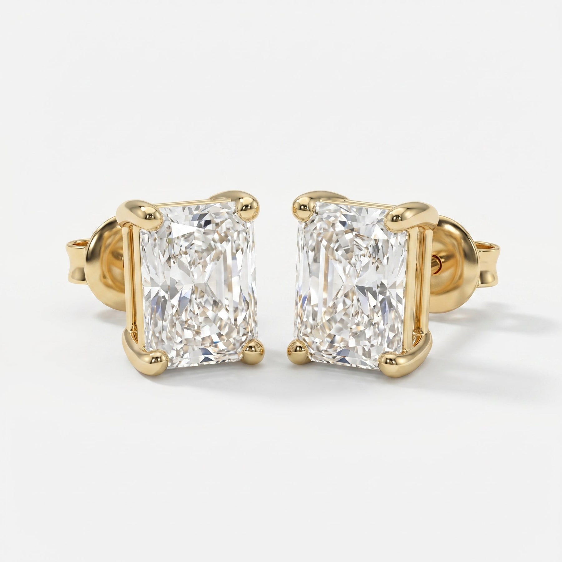 Gold earrings with rectangular cut diamonds on a white background