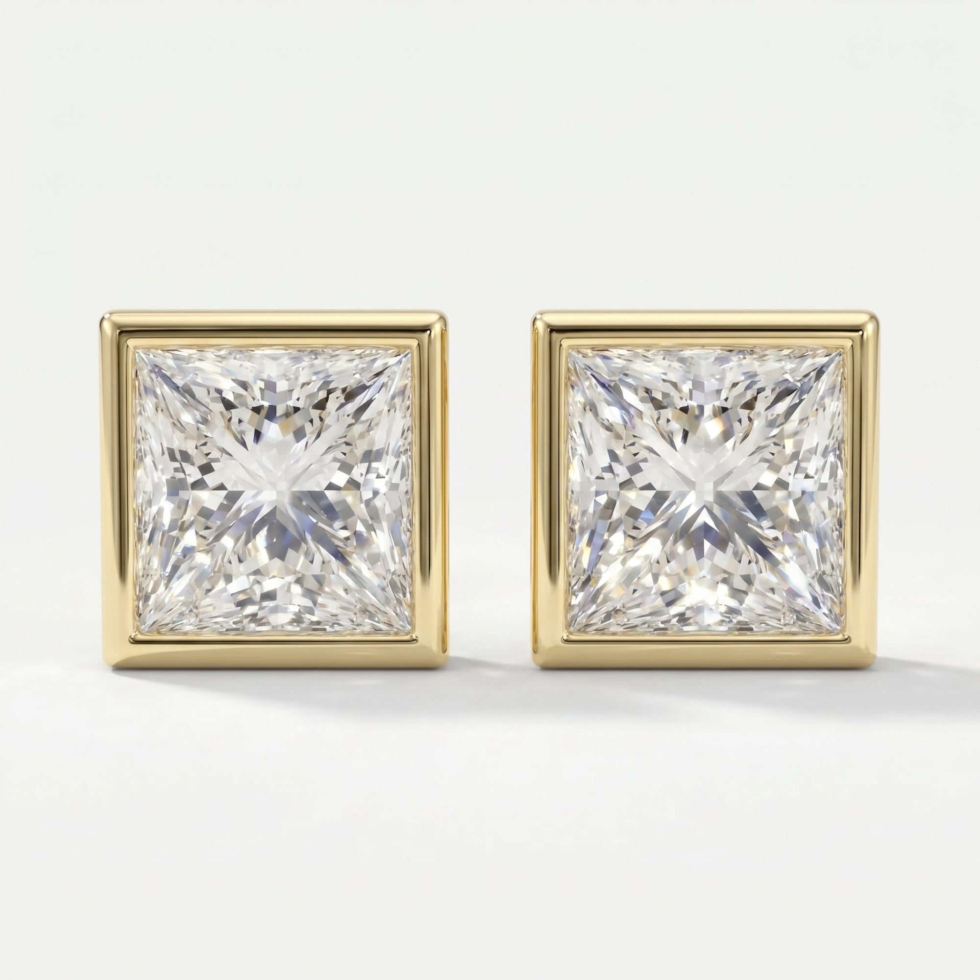 Pair of square-cut diamond earrings with gold prongs on a light gray background