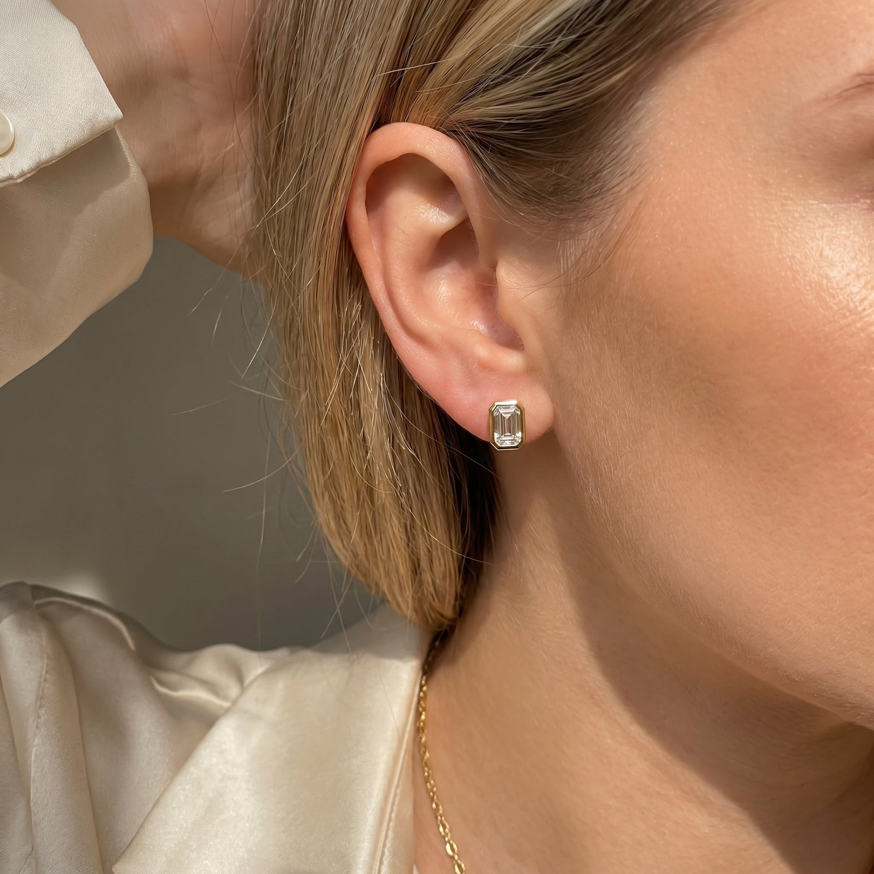 Close-up of a person wearing diamond earrings with a neutral background