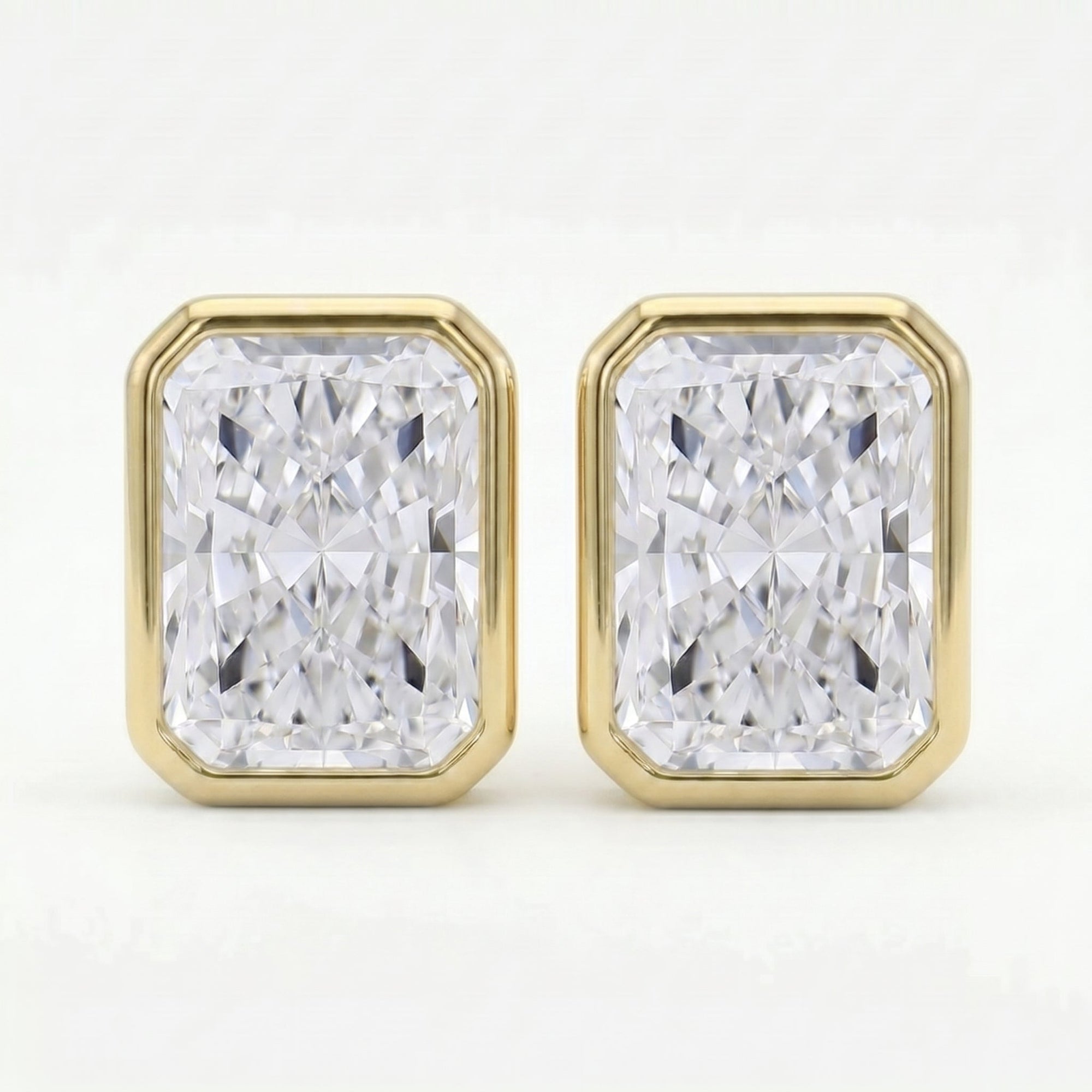 Gold earrings with rectangular diamond-like stones on a white background