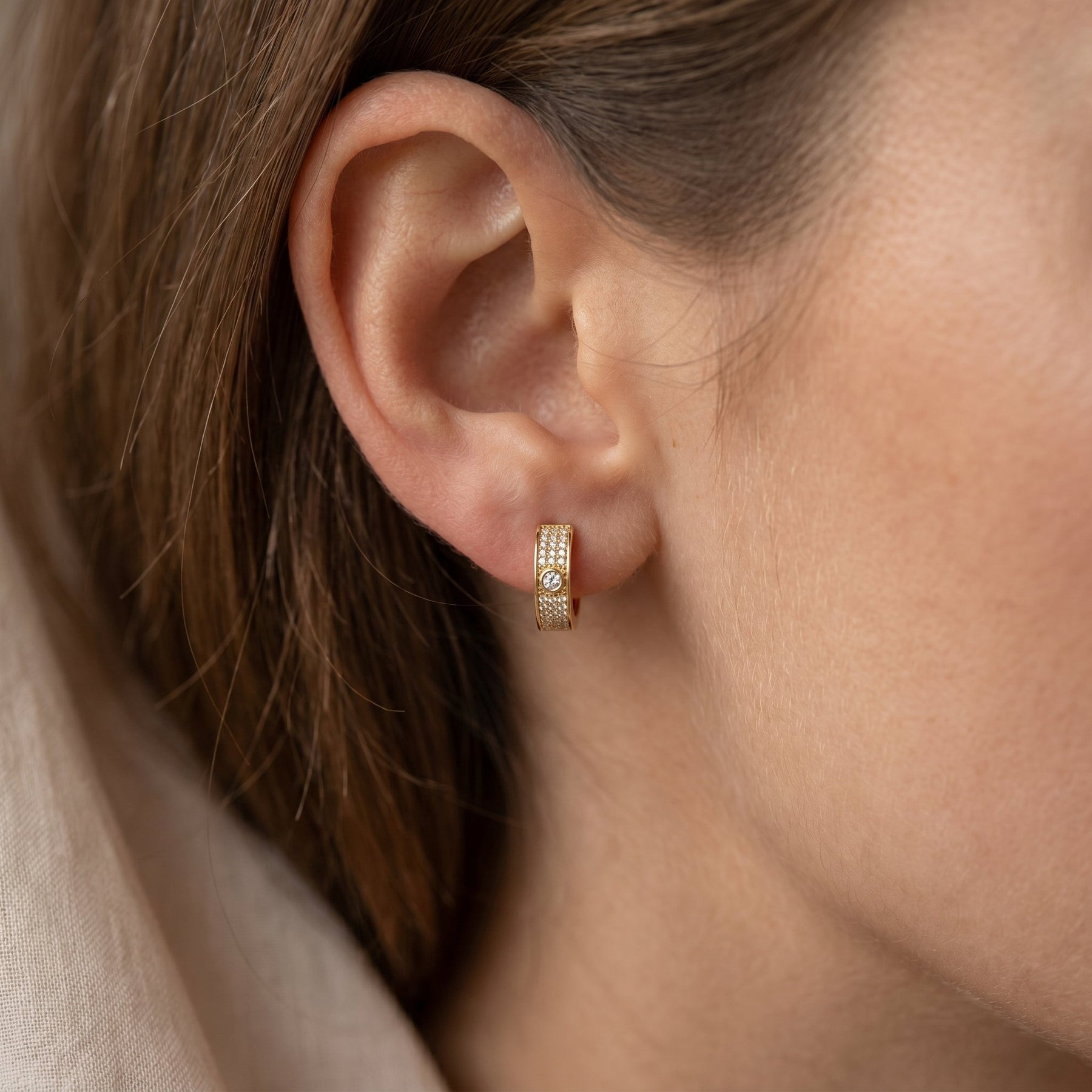 Woman wearing elegant rose gold diamond huggie hoop earrings in minimalist luxury lifestyle portrait